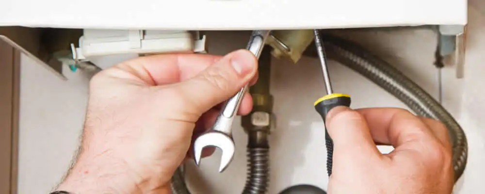 Boiler repair technician tightening pipe fittings and connections in Greenville, NC