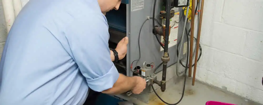 Furnace repair technician inspecting and servicing a home heating system in Greenville, NC