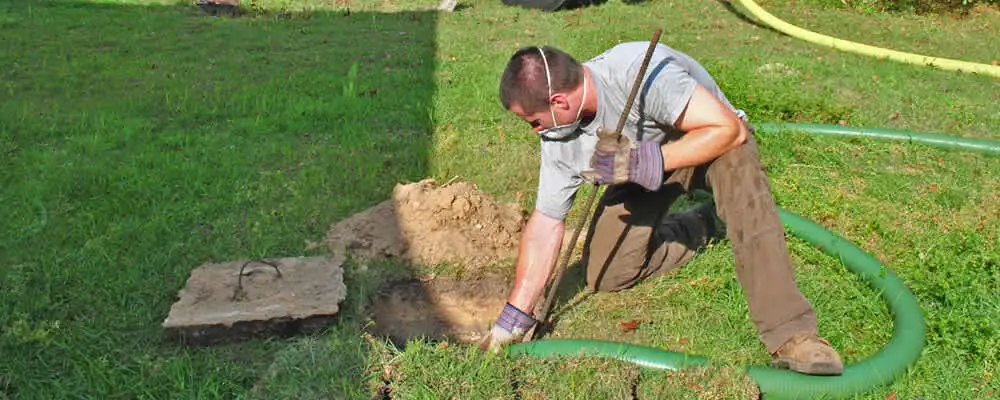 Septic pumping technician servicing a residential septic tank in Greenville, NC