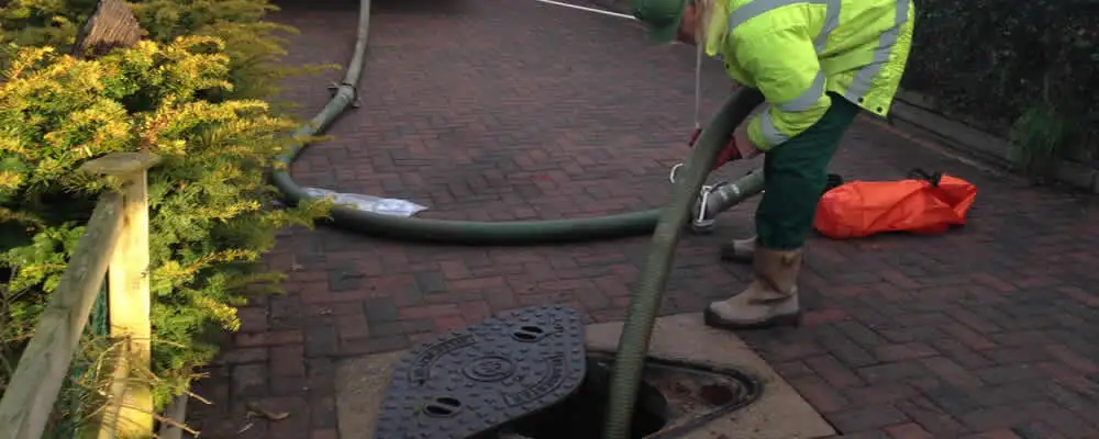 Septic tank cleaning technician servicing a septic tank with a vacuum hose in Greenville, NC