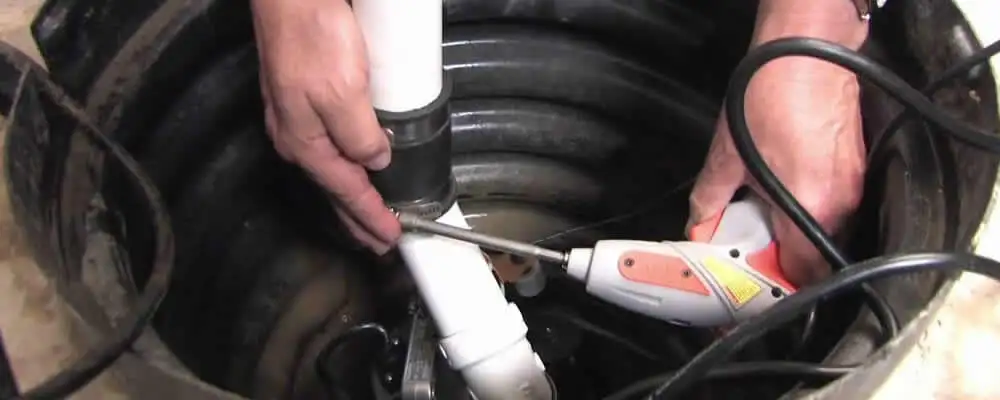 Sump pump installation technician connecting PVC discharge piping in Greenville, NC