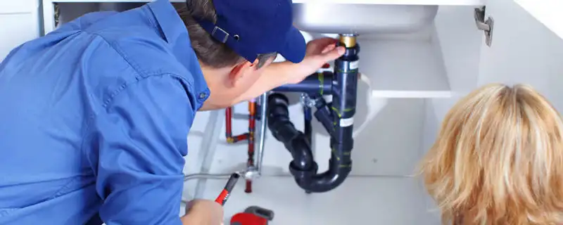 Plumber repairing under-sink drain pipes and fittings in Greenville, NC